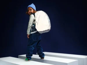 Ein Kind trägt einen Schulranzen von ergobag mit einer vollreflektierenden Regenhülle.