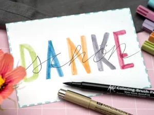 Weiße Postkarte auf die mit Stiften von Sakura „Danke schön“ gelettert wurde. Foto: Johanna Rundel