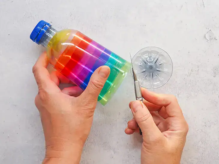 Jemand schneidet den Boden von einer angemalten PET-Flasche ab. Foto: Johanna Rundel