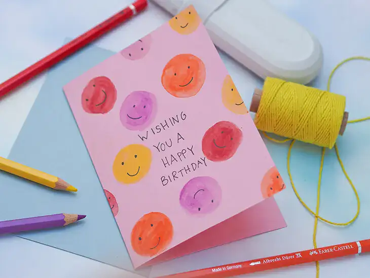 Eine rosa Klappkarte mit aquarellierten Smileys und dem Spruch „Wishing you a Happy Birthday“. Foto: Johanna Rundel Eine rosa Klappkarte mit aquarellierten Smileys und dem Spruch „Wishing you a Happy Birthday“. Foto: Johanna Rundel